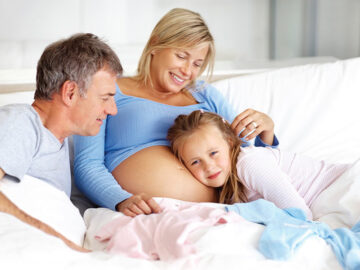 Pregnant woman with her daughter listening to her baby