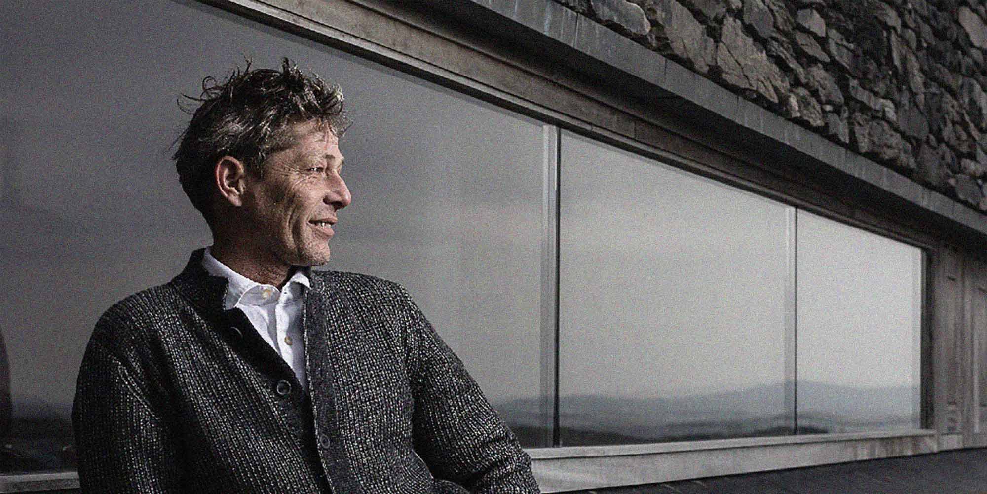 Pictiúr d'úinéir Cniotáil Inis Meáin taobh amuigh dhá siopa agus é ag caitheamh ceann dhá chuid geansaithe