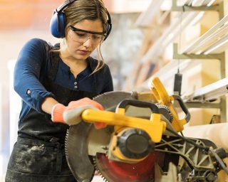 Woman using a mechanical saw in a workshop