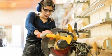 Woman using a mechanical saw in a workshop